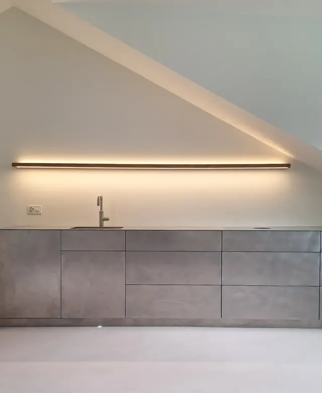 STUDIOLIVIUS Einbauküche aus Edelstahl grifflos in Dachgeschoss mit rosa Spachtelboden und Einbauschrank in weiß im Kanton Glarus, Schweiz
