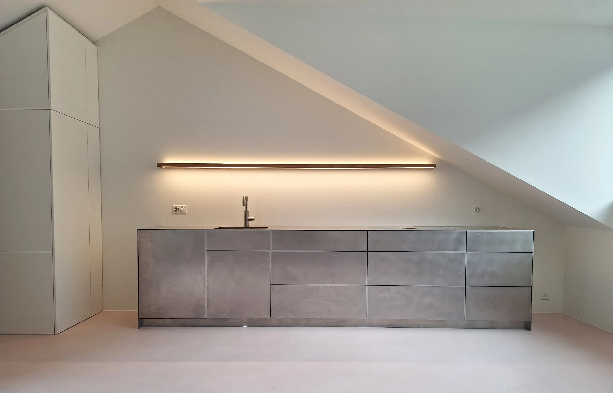 STUDIOLIVIUS Einbauküche aus Edelstahl grifflos in Dachgeschoss mit rosa Spachtelboden und Einbauschrank in weiß im Kanton Glarus, Schweiz