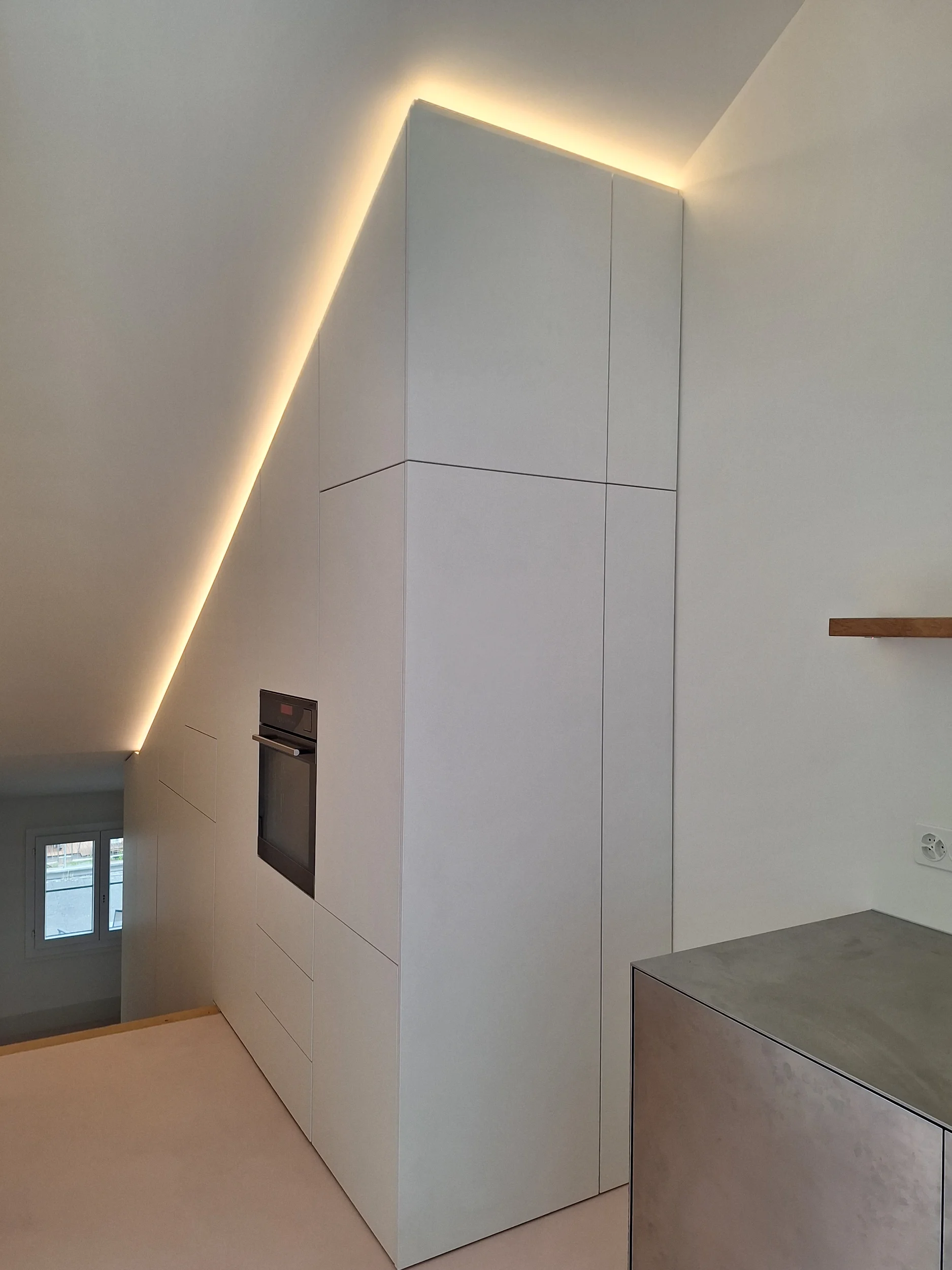 STUDIOLIVIUS Einbauküche aus Edelstahl grifflos in Dachgeschoss mit rosa Spachtelboden und Einbauschrank in weiß im Kanton Glarus, Schweiz