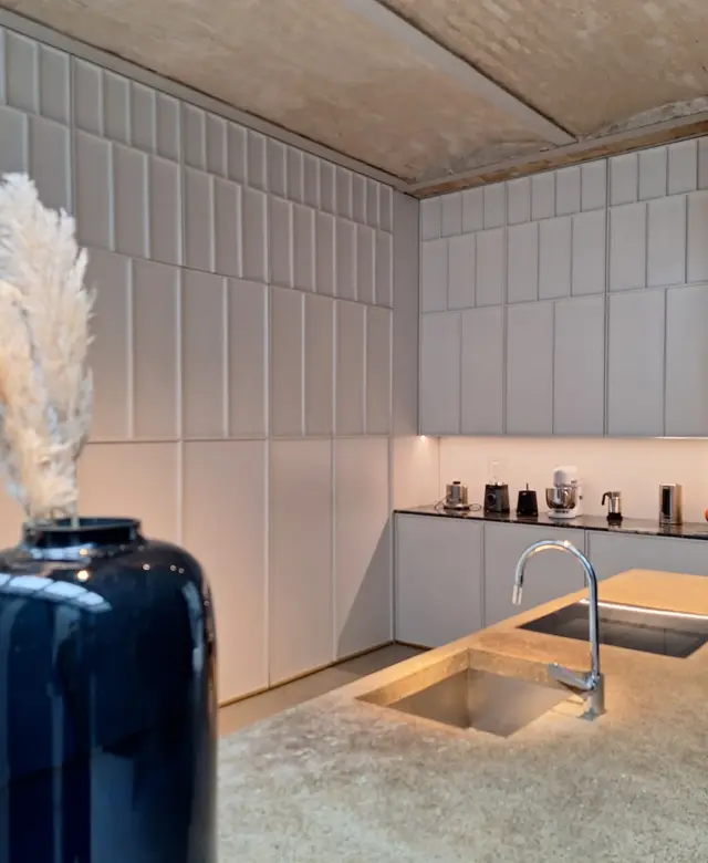 Moderne Wohnküche in einer Berliner Remise mit einer Kücheninsel aus Eiche und Beton sowie einer raumhohen, weißen Schrankwand im Goldenen Schnitt von STUDIOLIVIUS.